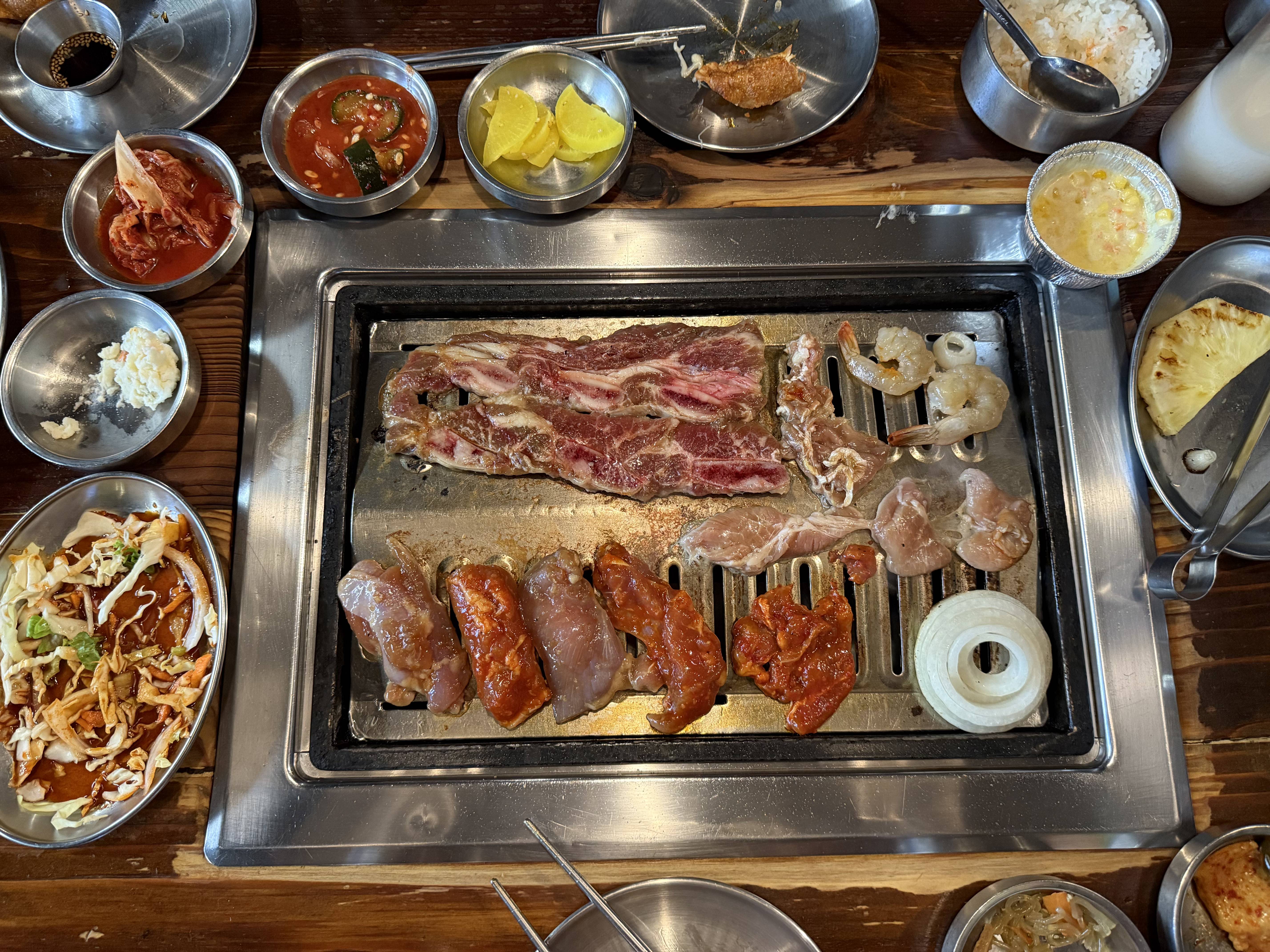 meat on a grill with a variety of banchan