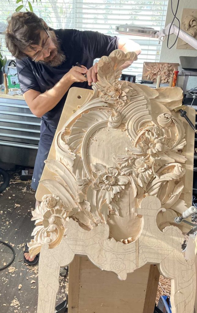 A man carves an intricate pattern into wood