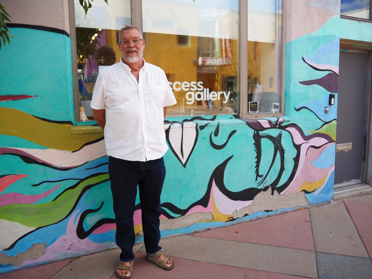 A man stands in front of a blue mural