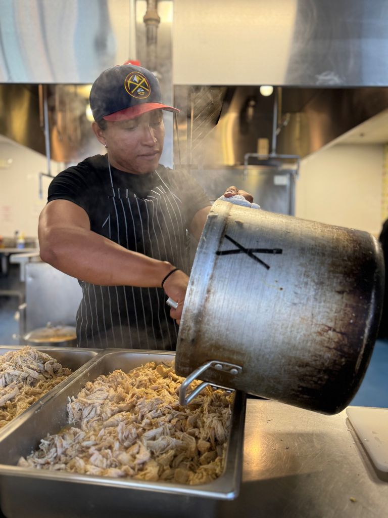 Edwin Sandoval transferring a large pot of cooked meat to a metal pan