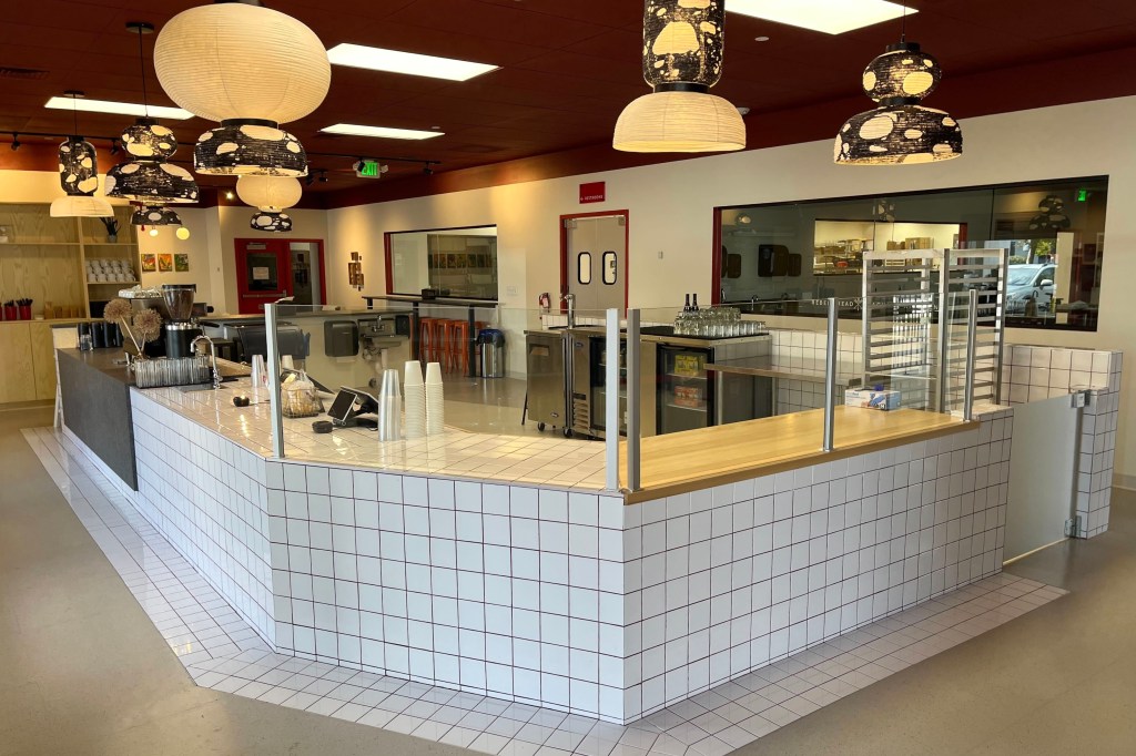 A white-tiled counter and accent light fixtures inside the new Rebel Bread cafe