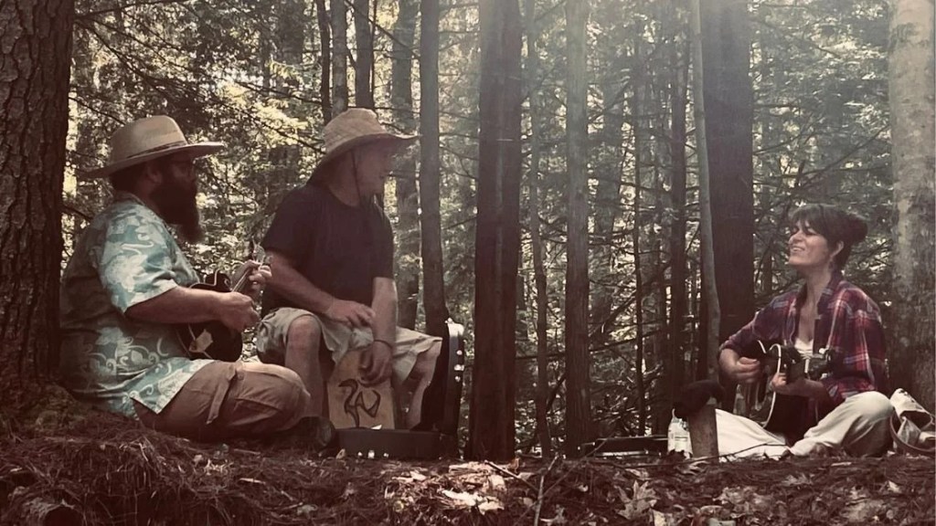 three musicians sitting in a forest