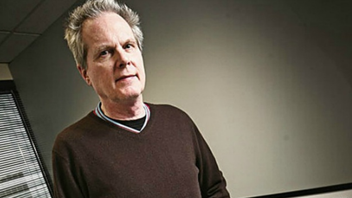 A portrait of a man in a brown sweater