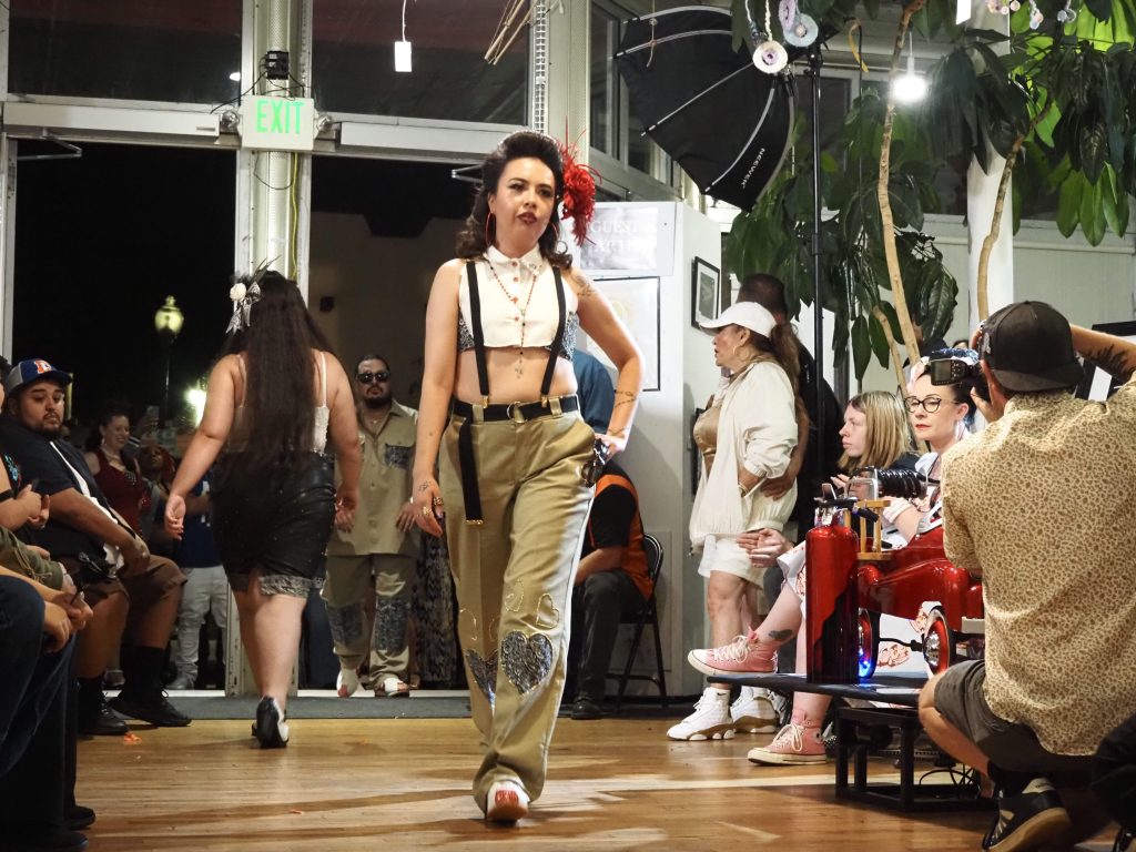 A person in suspenders walks a runway