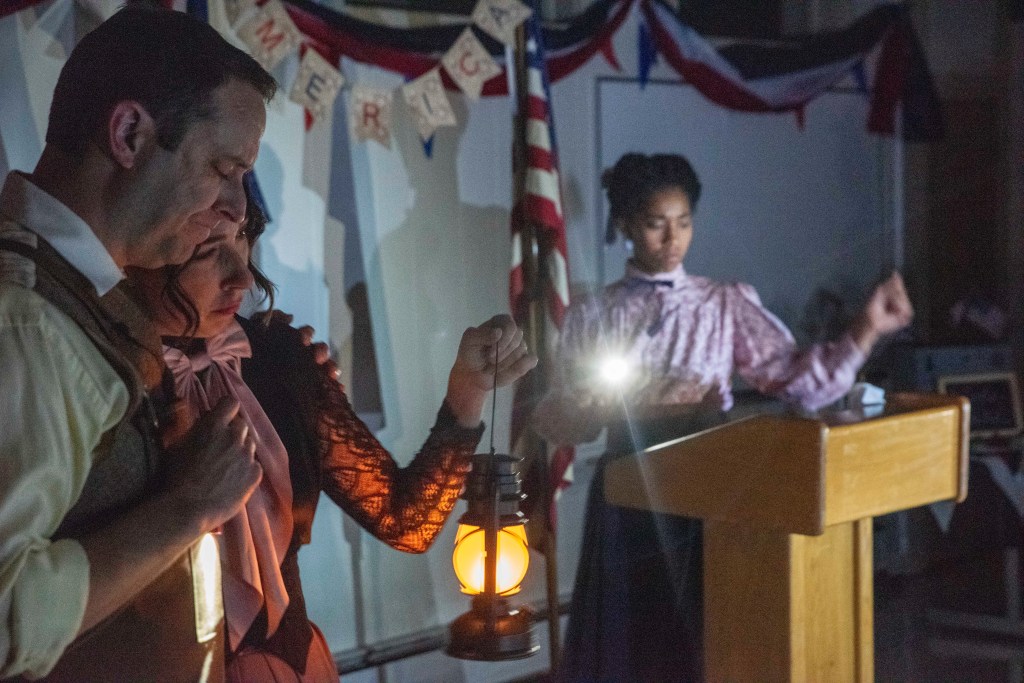 A woman holding a lantern and man lean on each other as a women stands with a flashlight behind them.