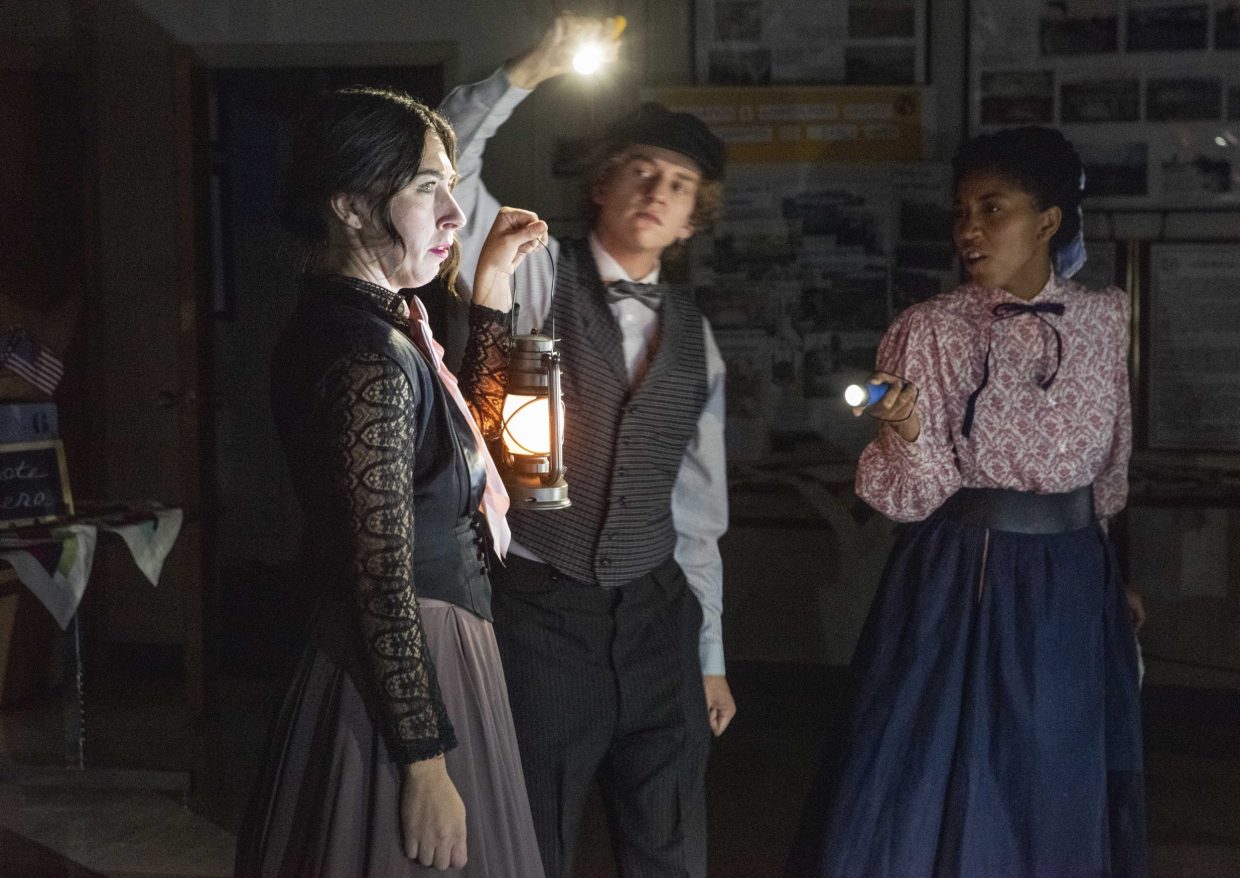 A woman holds a lanterns as two people hold flashlights around them.