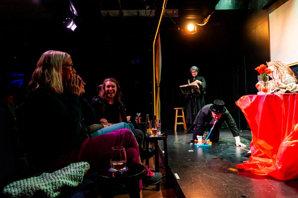 Audience laughs as a man vomits onstage.