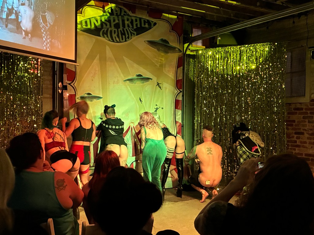 Performers present their butts to a crowd.