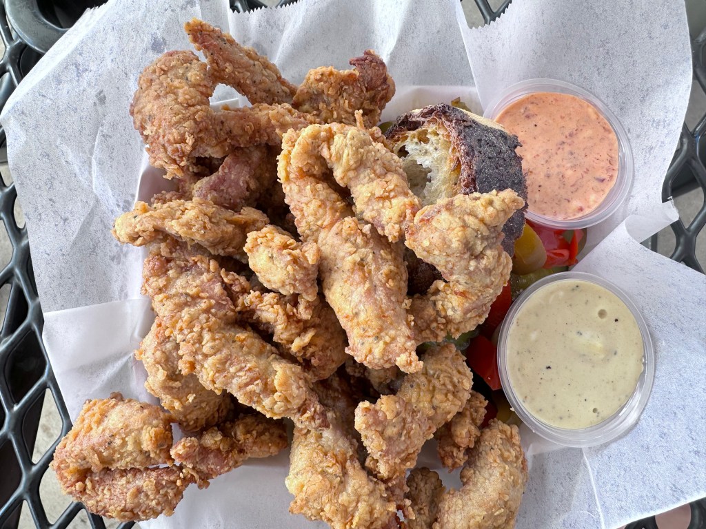 Schnitzel Bites served with pickled vegetables, rye bread, and tartar sauce.