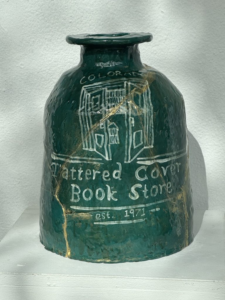 A green ceramic jar that says "tattered cover"