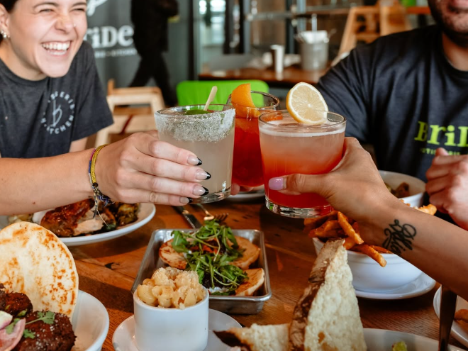 table full of food and people clinking glasses