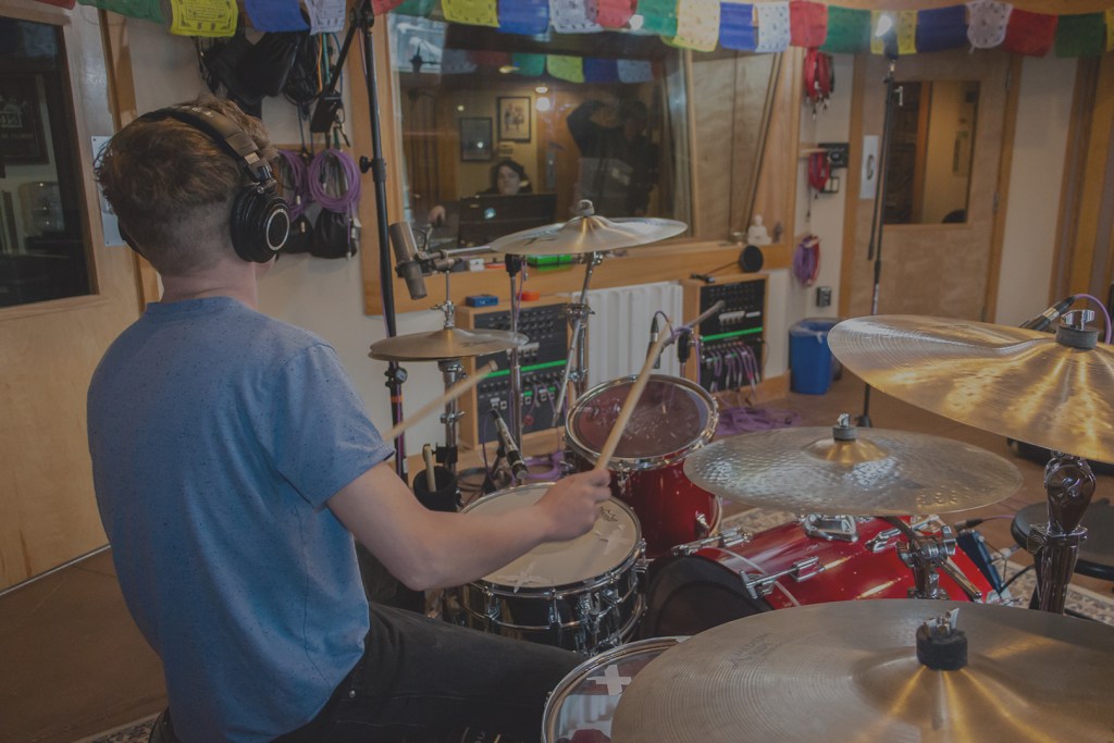 a studio recording room and drummer