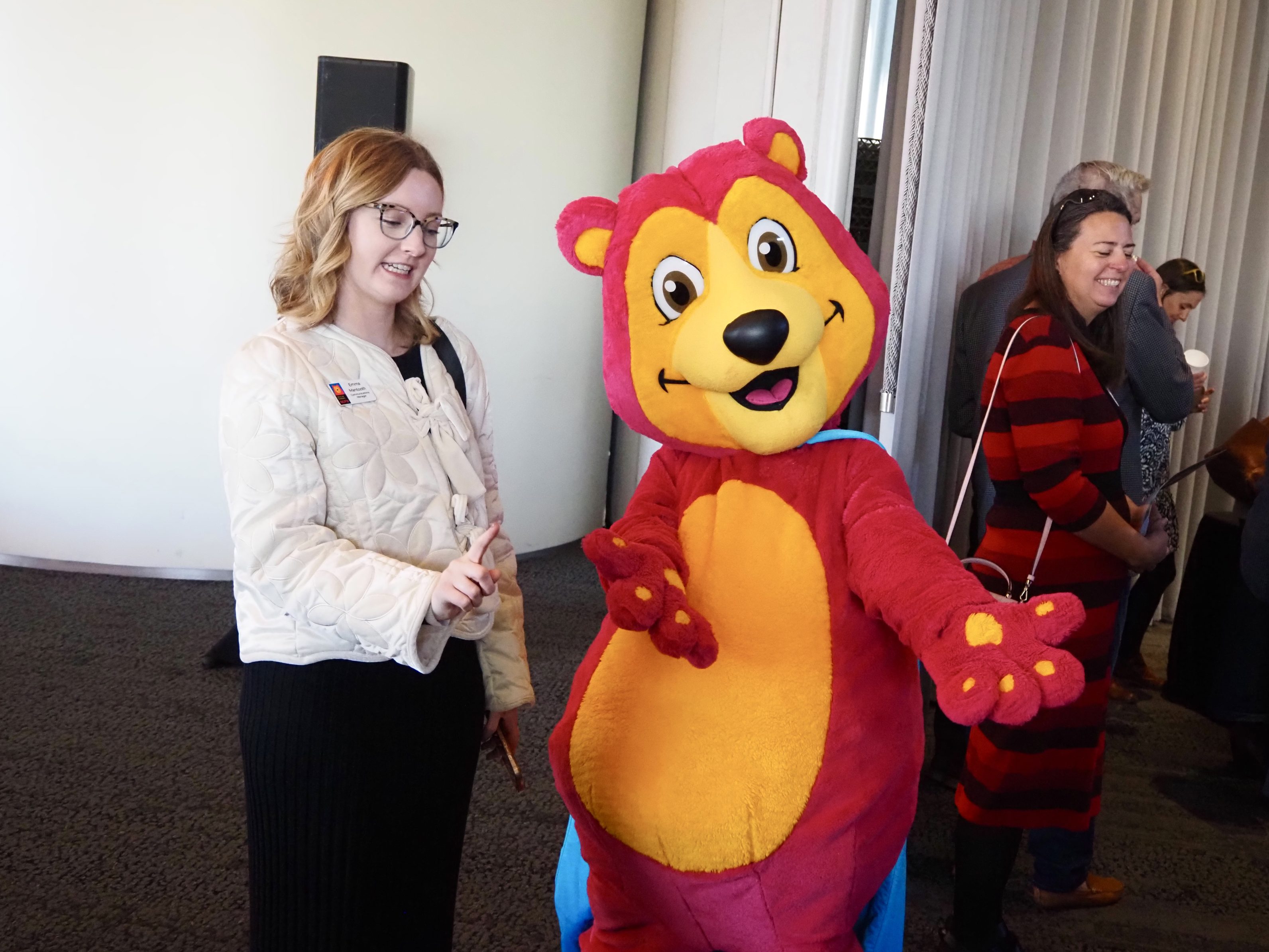 A magenta bear mascot poses for a photo
