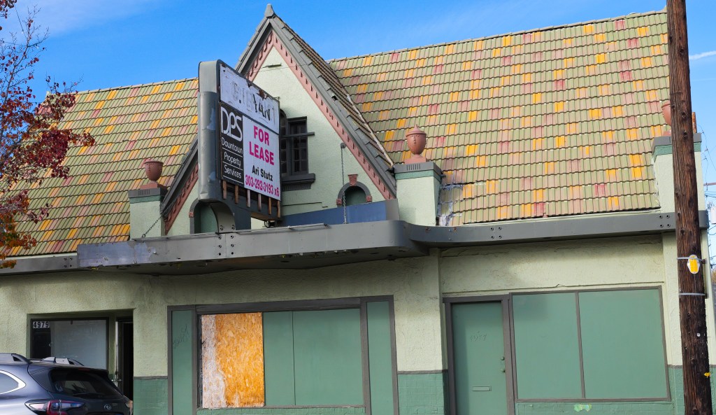 The exterior of a green building with a colorful roof