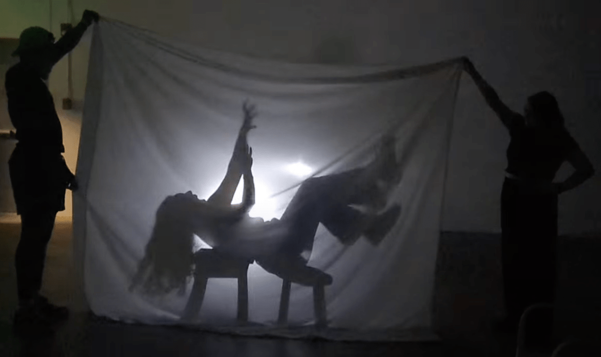 A theatrical shadow effect frames a person reaching up to the sky.