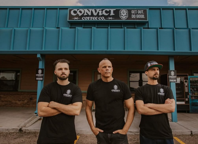 three men standing in front of a coffee shop