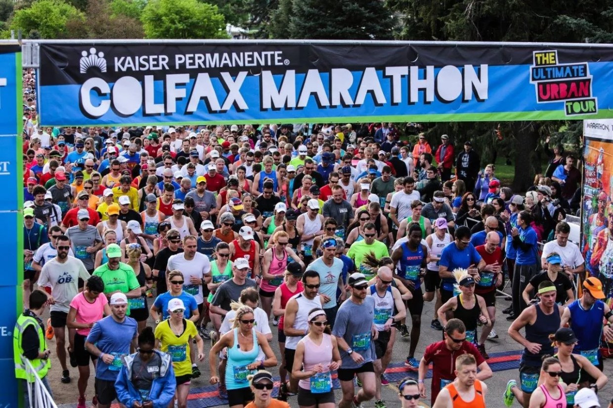 Runners take off under a banner reading "Colfax Marathon"