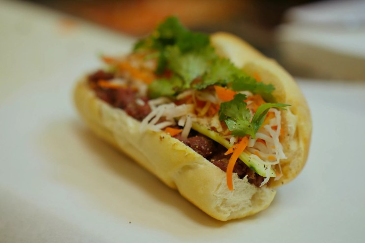 a sandiwch on a roll with veggies and herbs