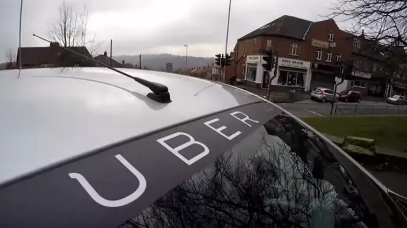 A white car displays the word UBER across the top of its windsheild.