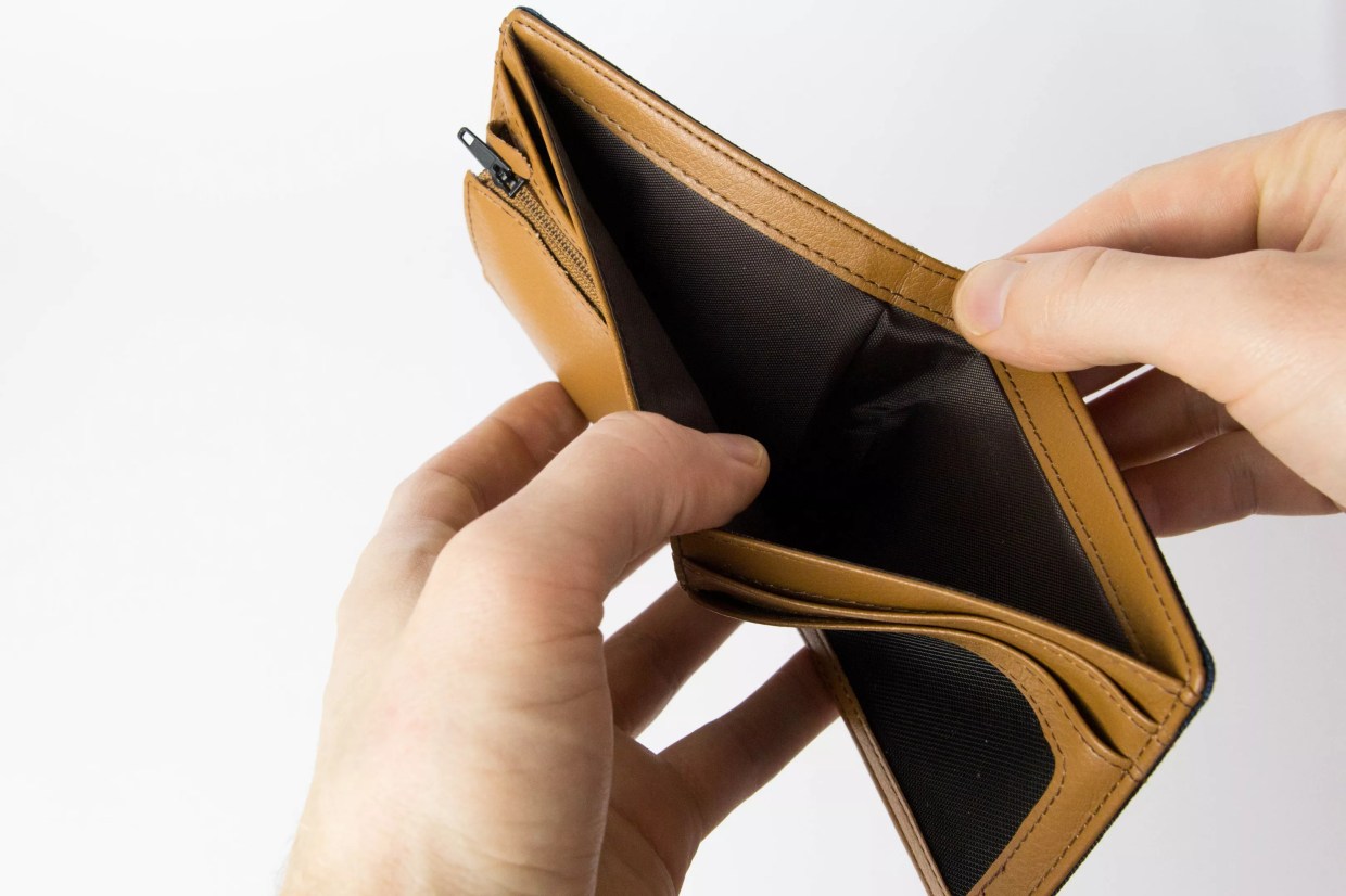 A pair of white hands pry open an empty wallet with their thumbs.