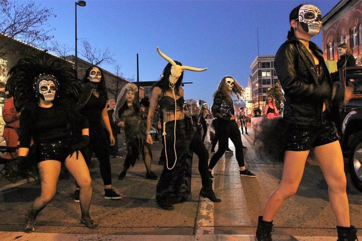 People in halloween masks and costumes dance on street