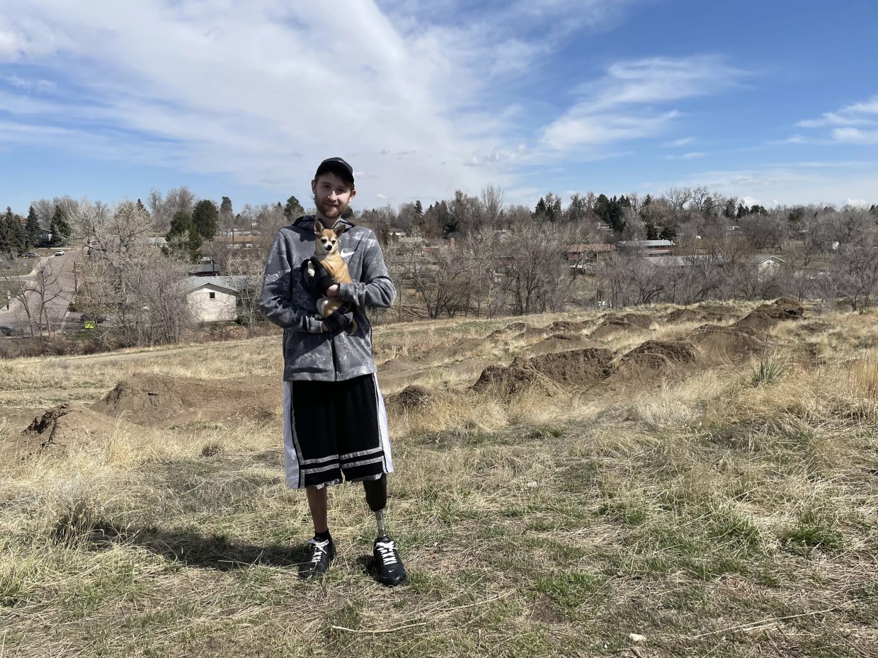 Man in hoodie stands outside on grass