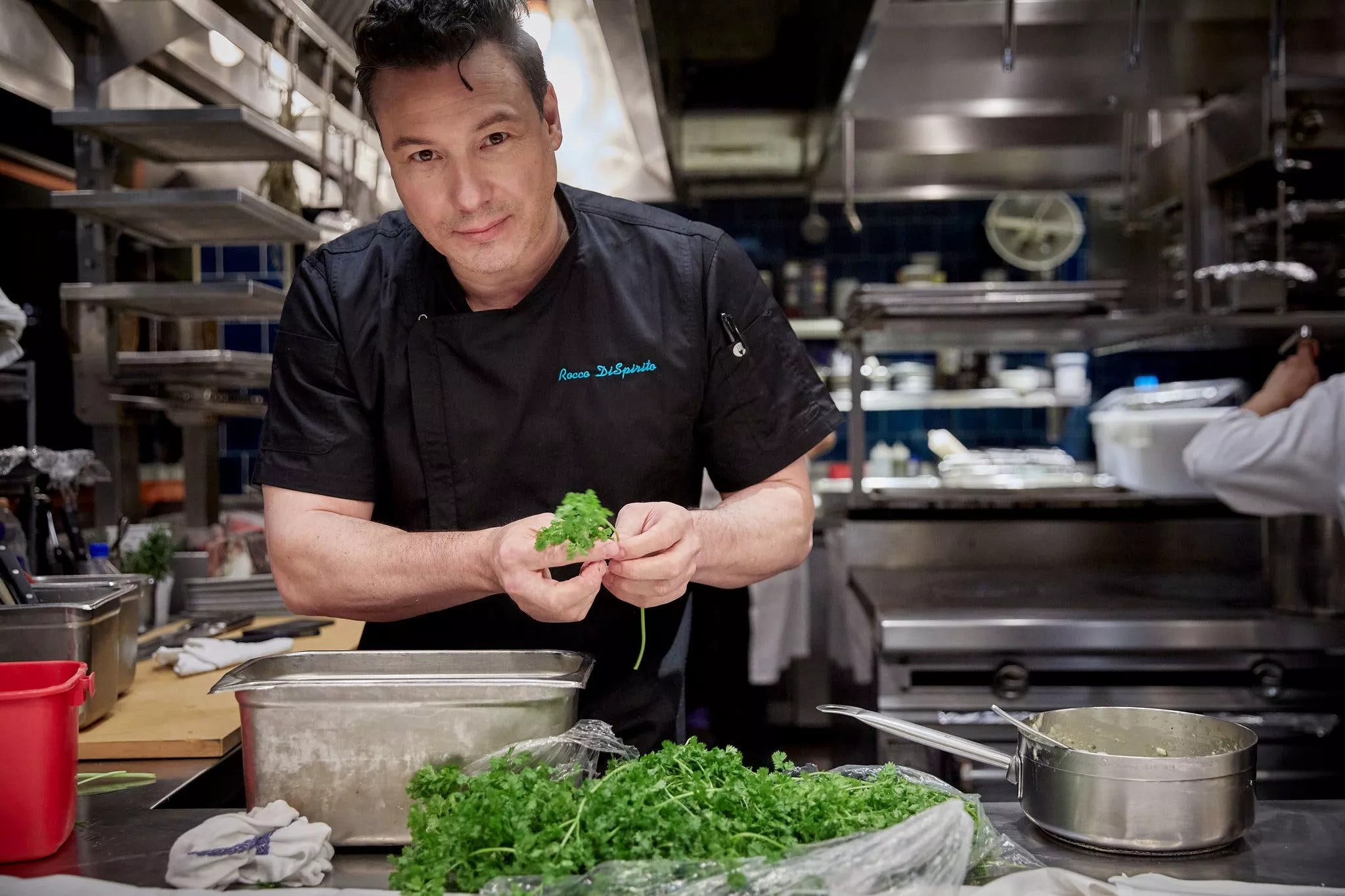 a man in an apron holding herbs