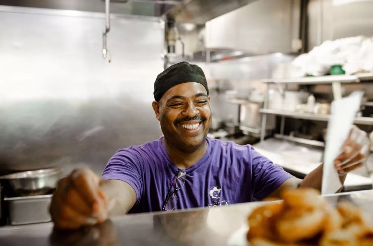 man in a purple shirt standing behind a counter