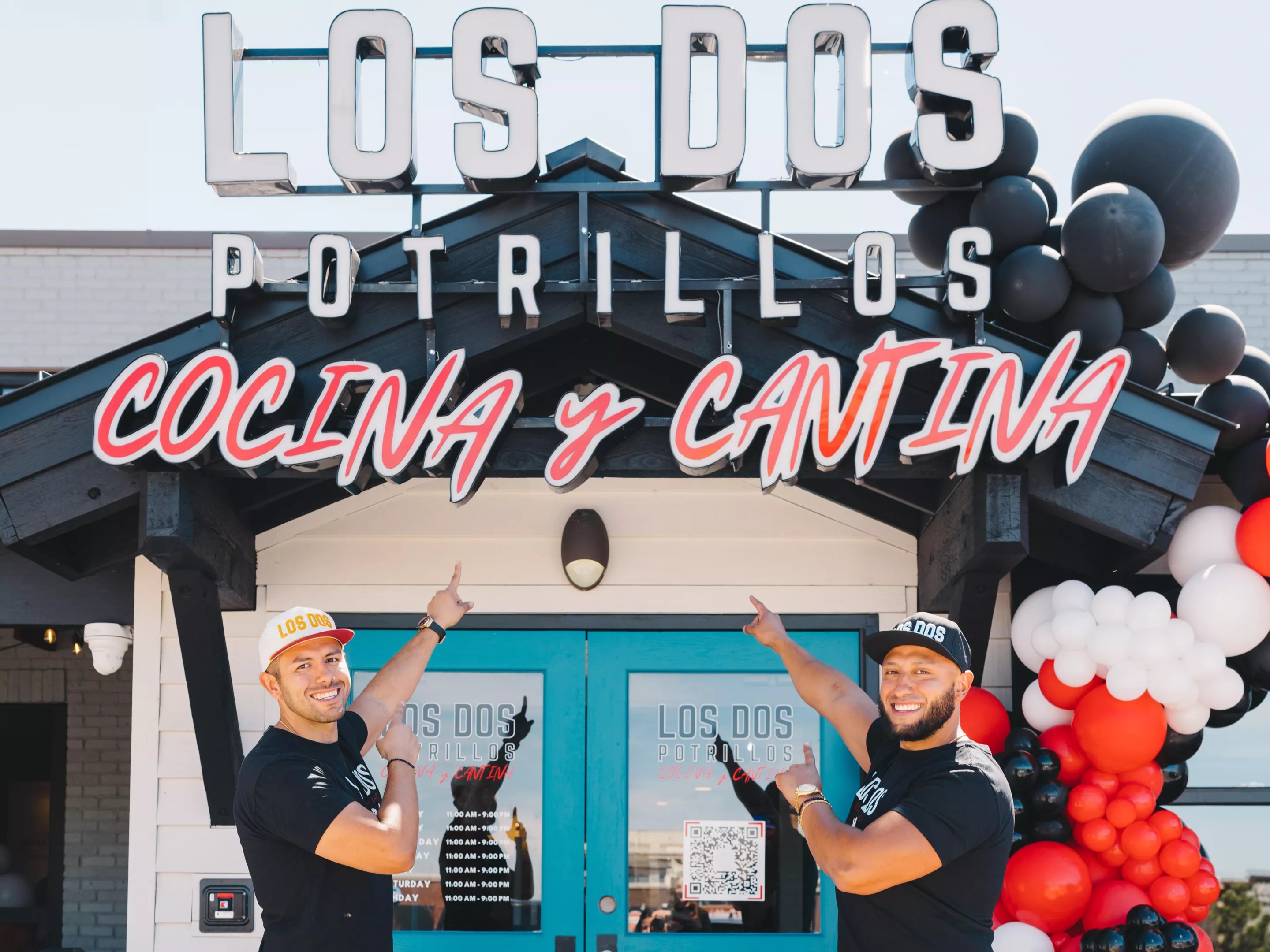 two men in front of a door pointing at building sign