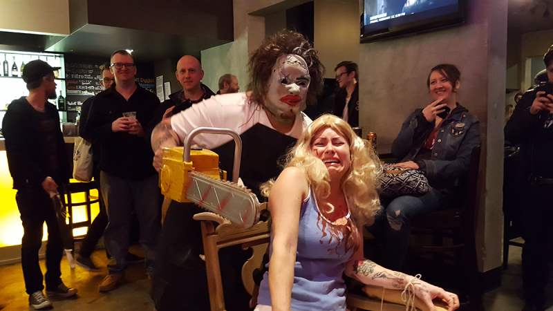 man with chainsaw woman blue dress and blonde wig