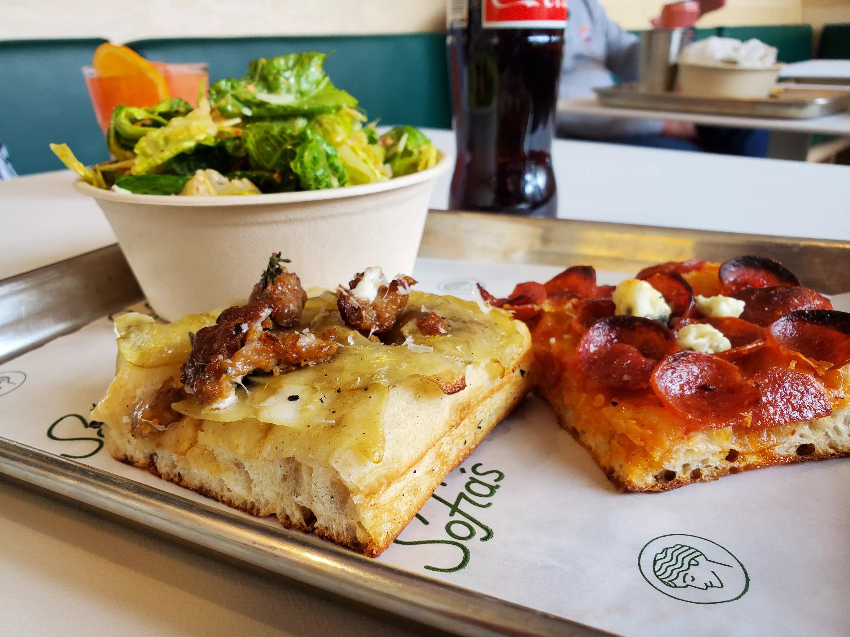 two slices of square pizza on a tray with a salad
