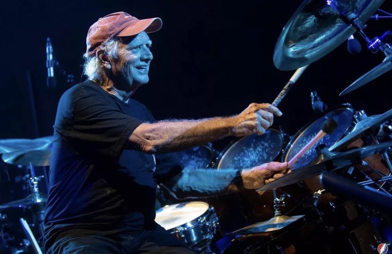 man playing drums in red hat