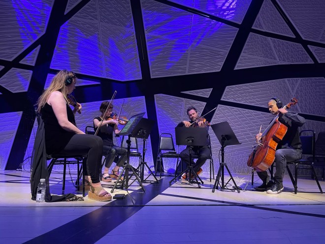 a string quartet performs amid blue lighting