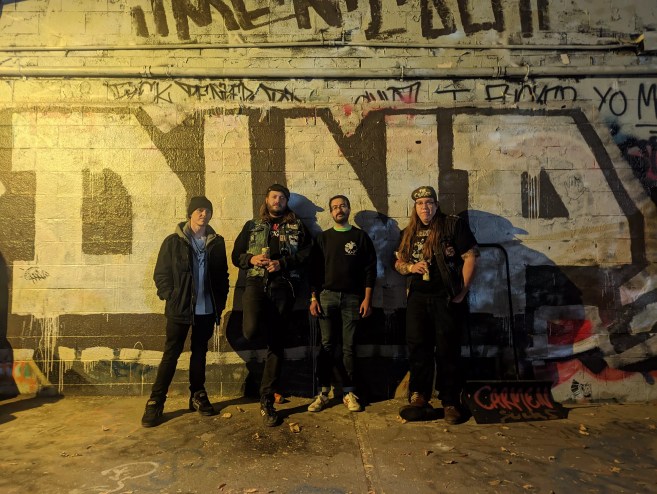 a punk band in front of graffiti