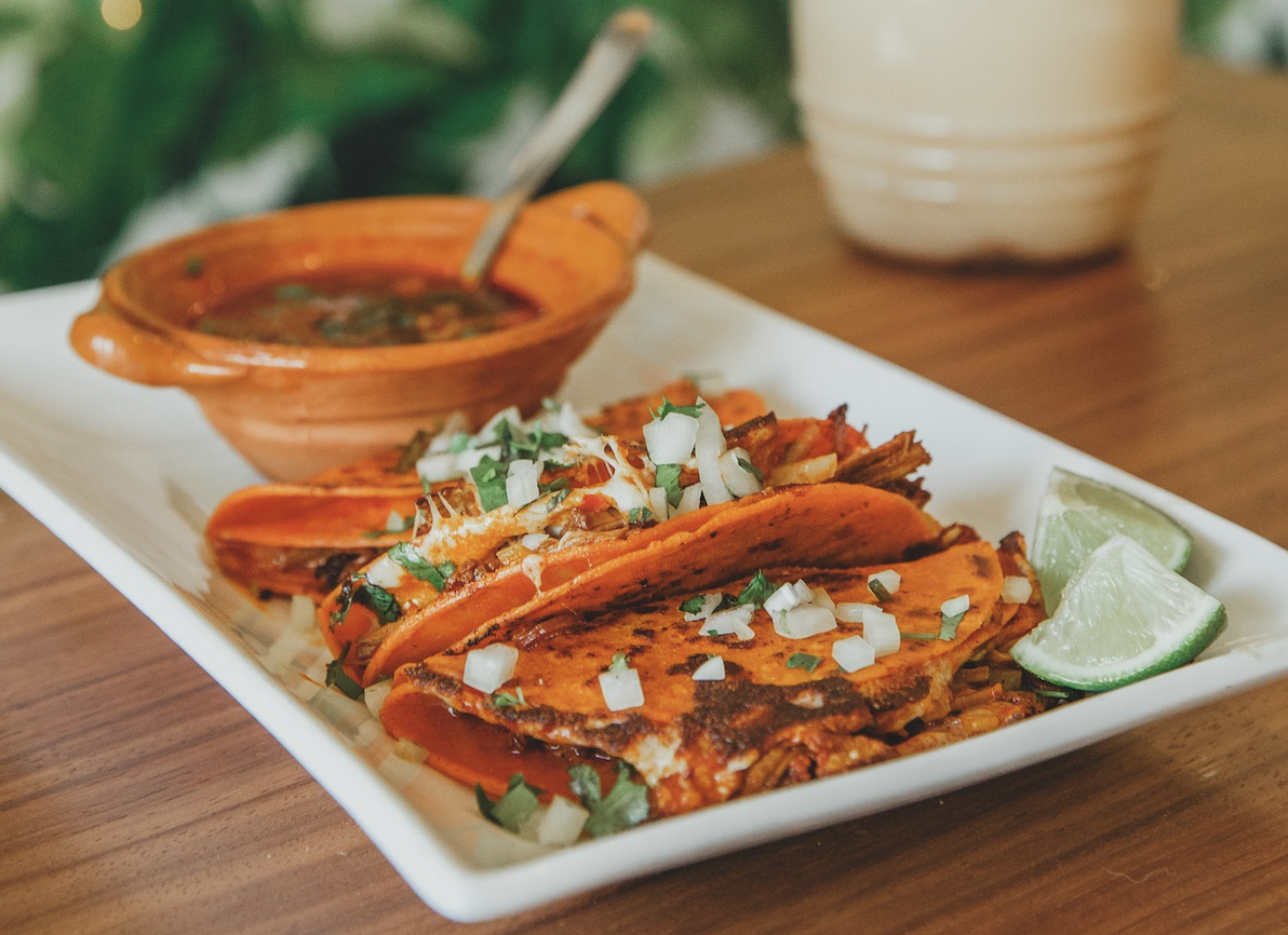 a plate of tacos with onions and cilantro on top