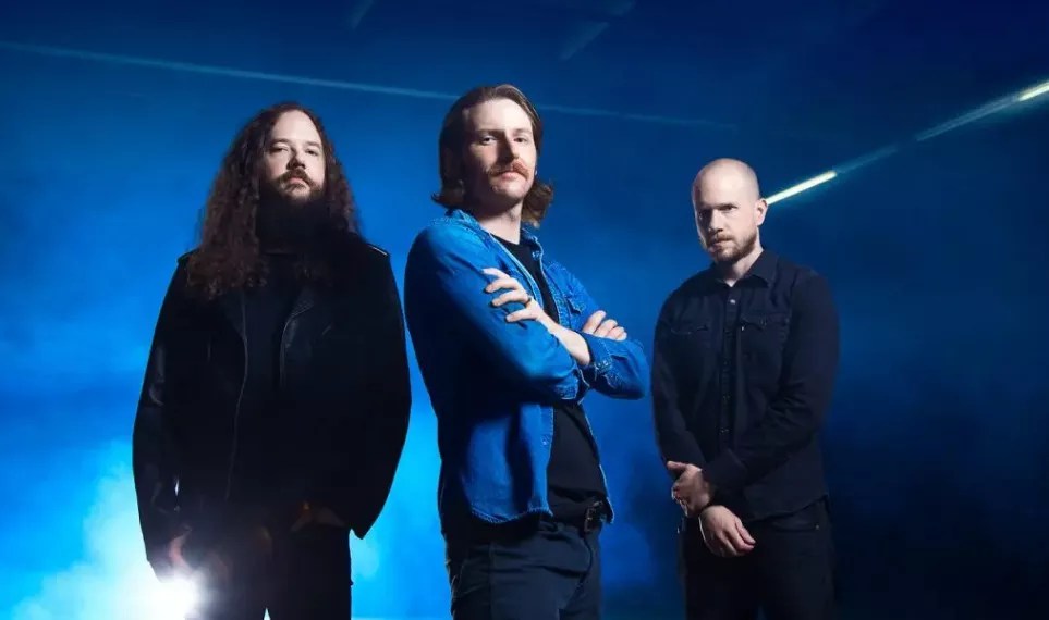 three men pose in a blue room