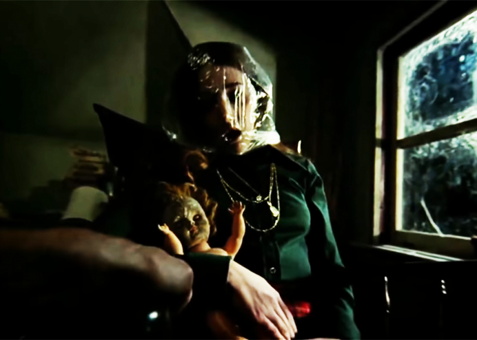 person with plastic over her face holding a creepy doll