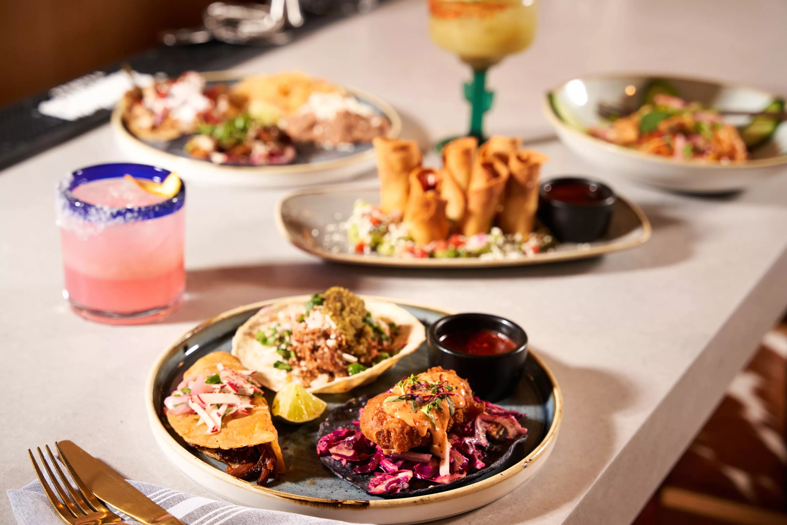 a plate of tacos, a margarita and other dishes on a table