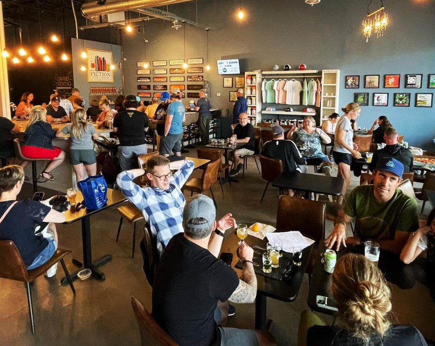 people sitting at tables inside a brewery