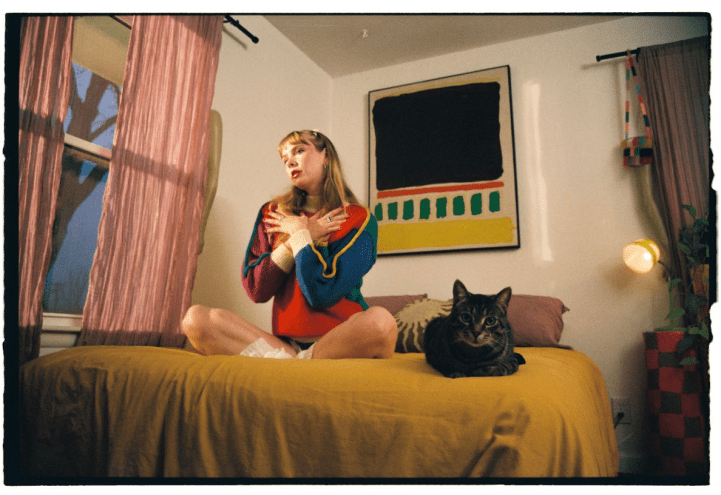 woman sits on bed with black cat