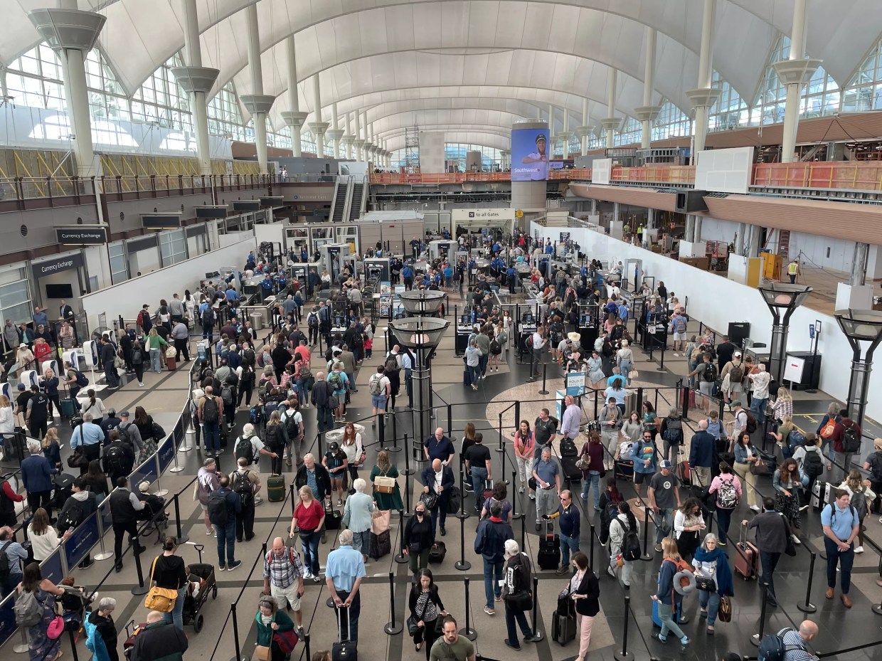 People wind their way through a security line in a hall with a domed roof.