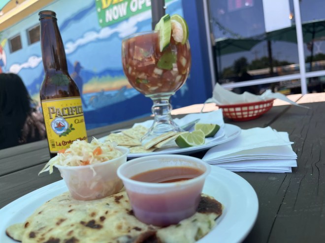 beer in a bottle next to shrimp cocktail in a large glass
