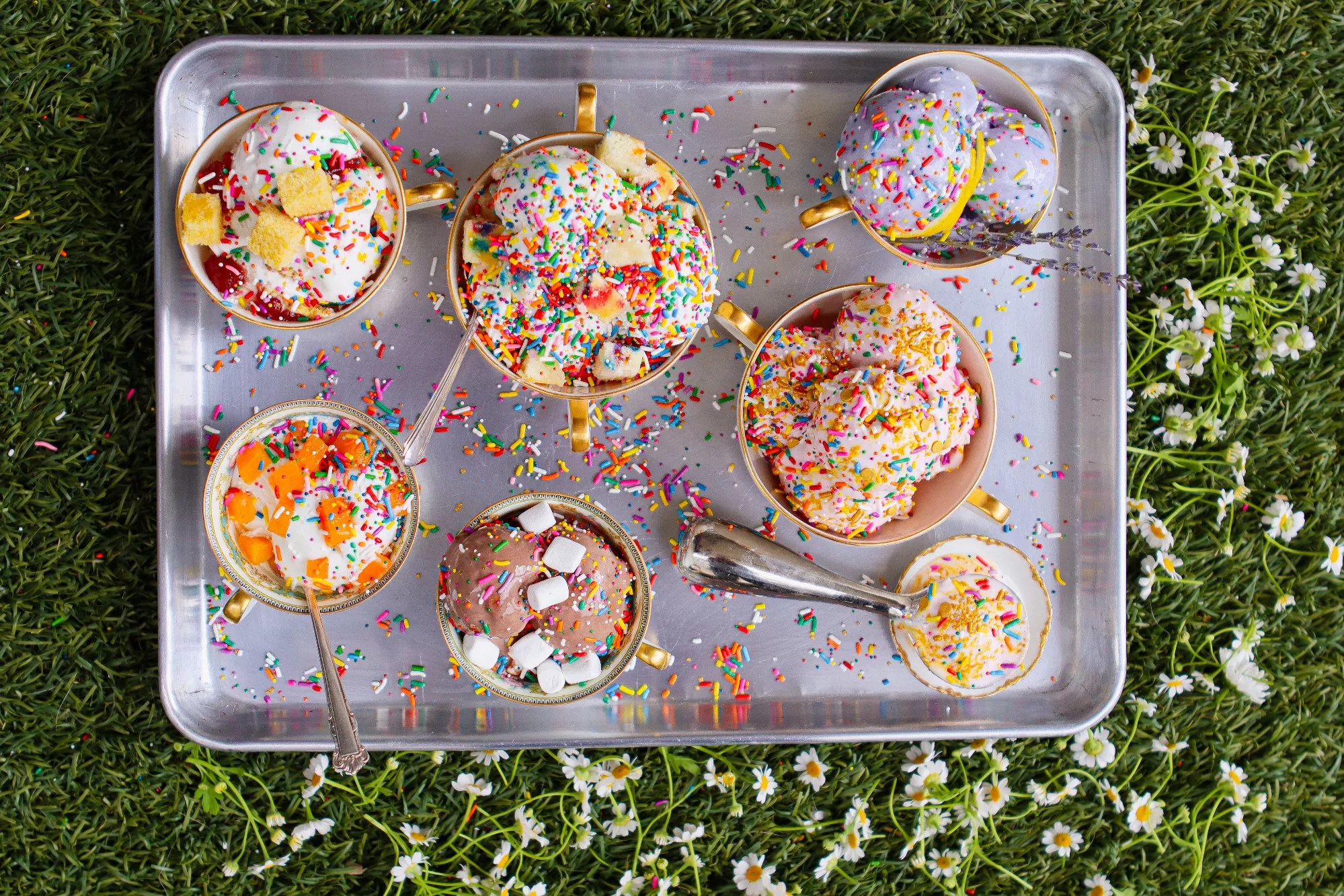an overhead shot of scoops of ice cream in cups covered in sprinkles