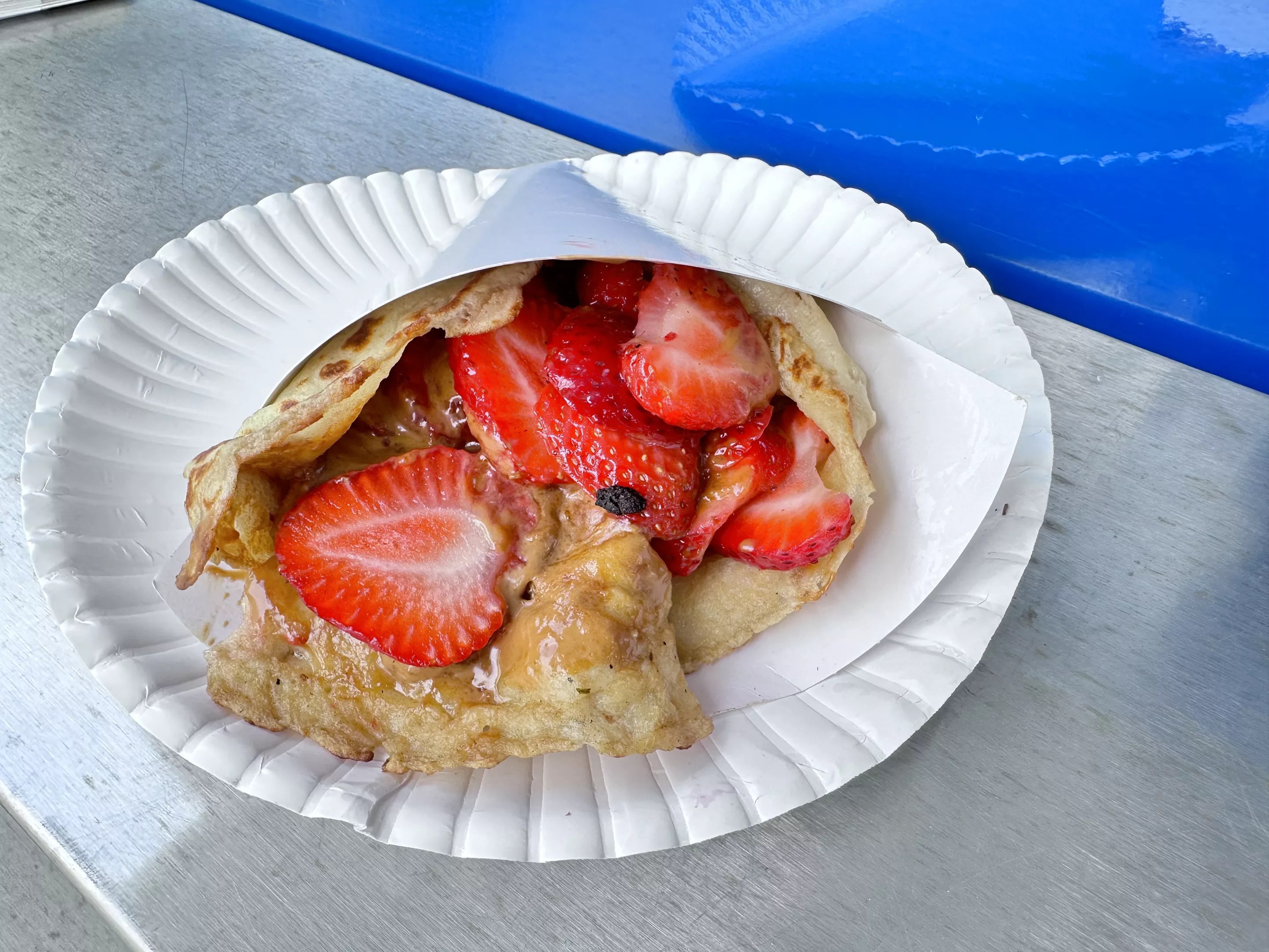 a crepe on a paper plate filled with strawbeerries
