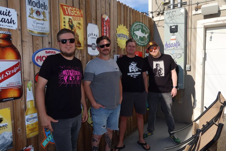 four men standing in front of a bar