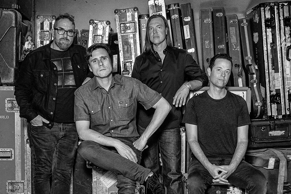four men standing in front of music equipment