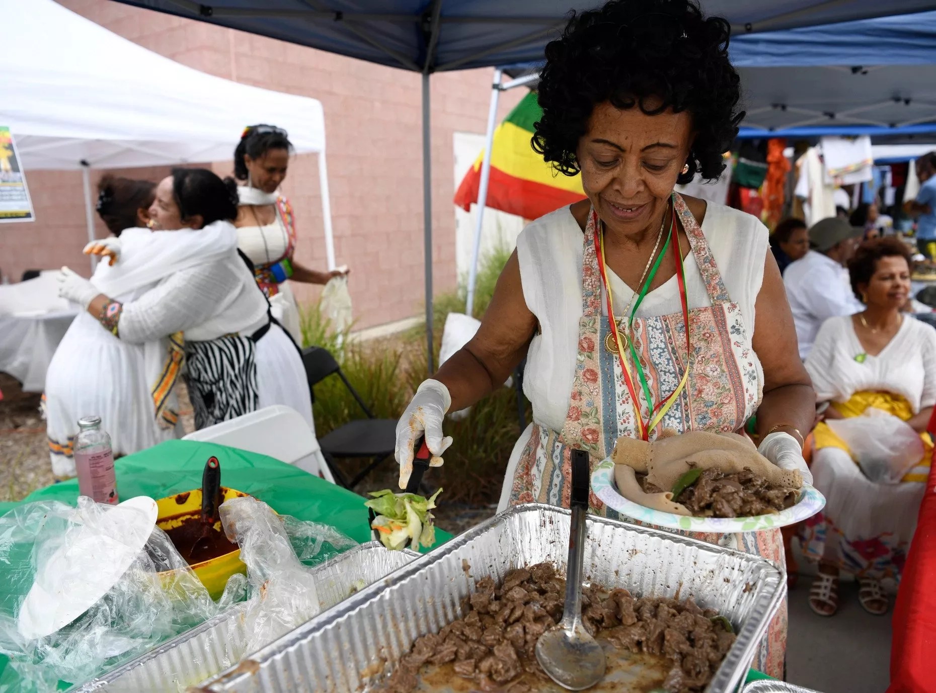 A woman serving a plate of injera and other Ethiopian dishes