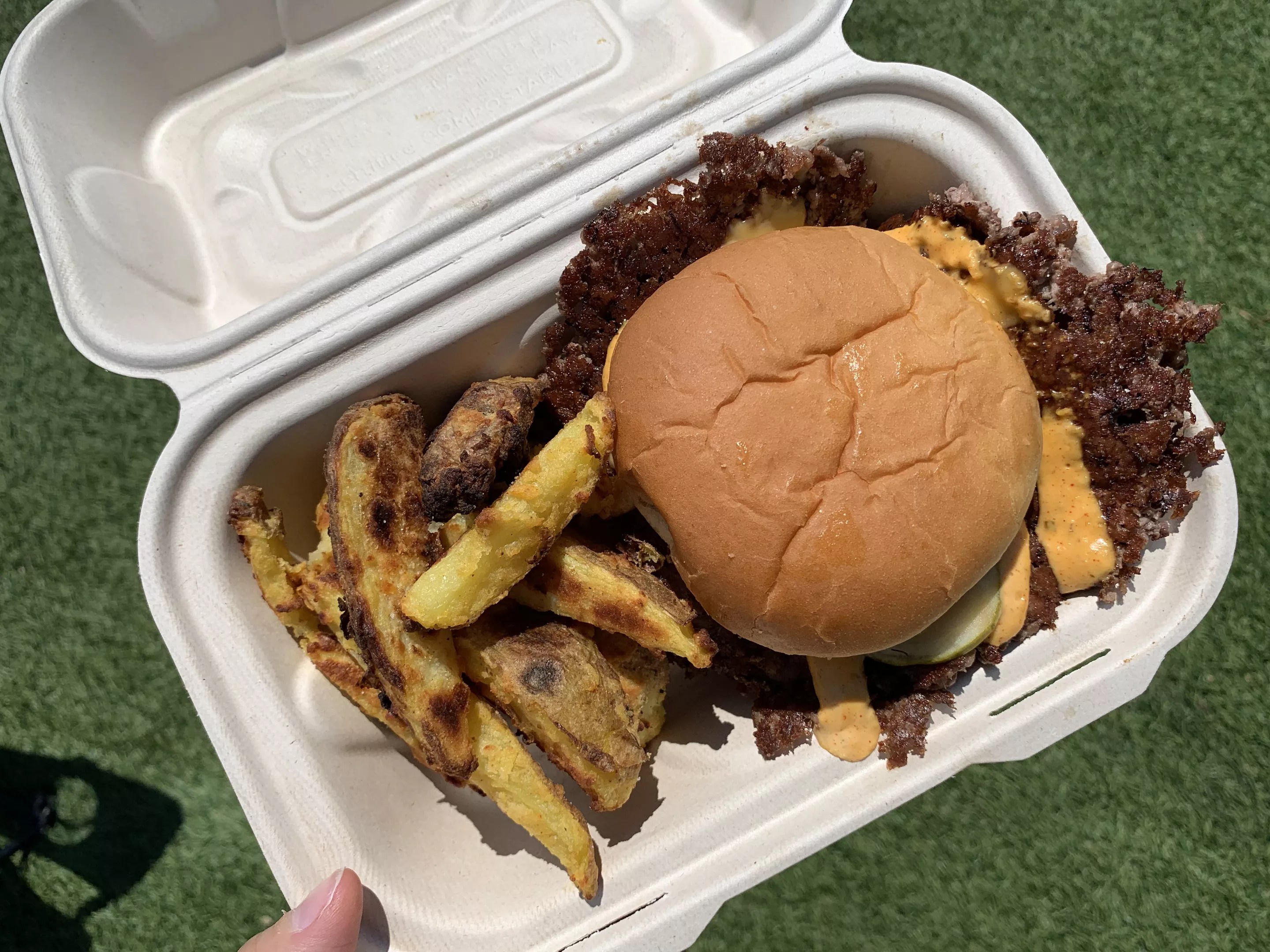 to go box filled with potato wedges and a cheeseburger