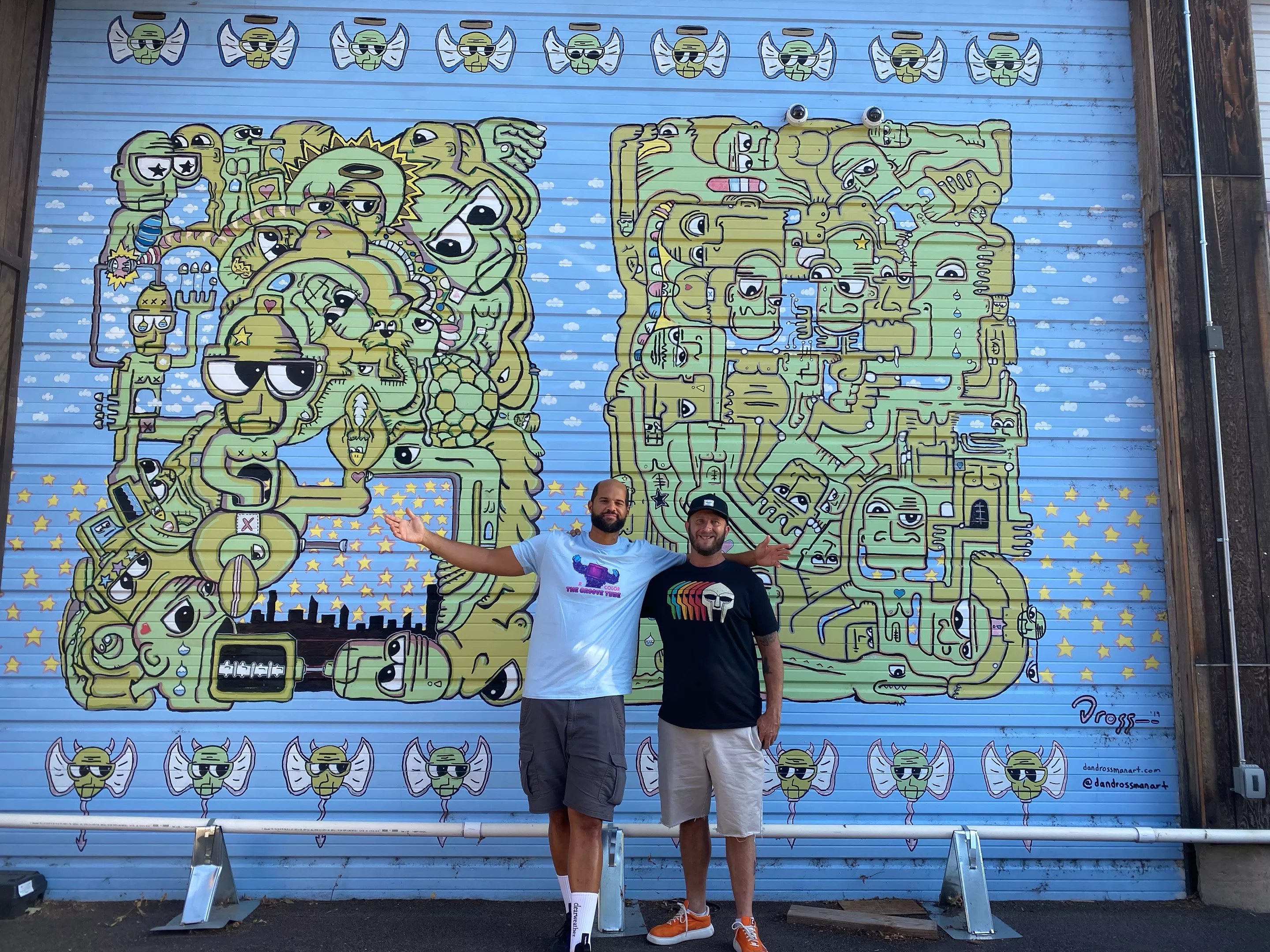 two men standing in front of a mural
