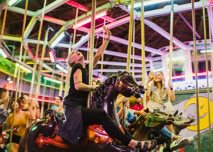 woman rides on lit-up carousel